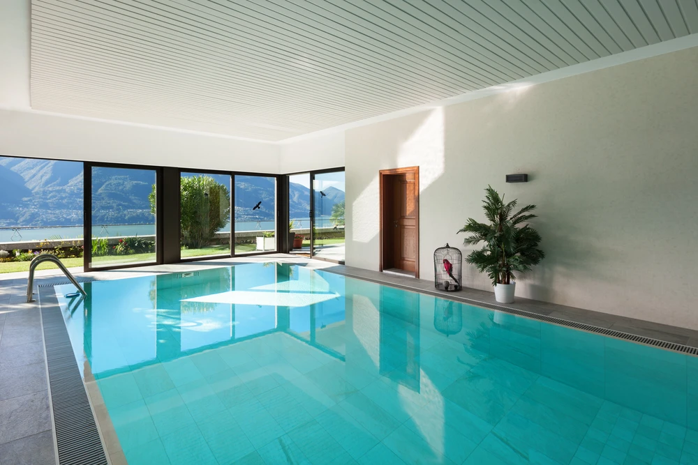 Piscine intérieure moderne avec vue panoramique sur lac et montagnes