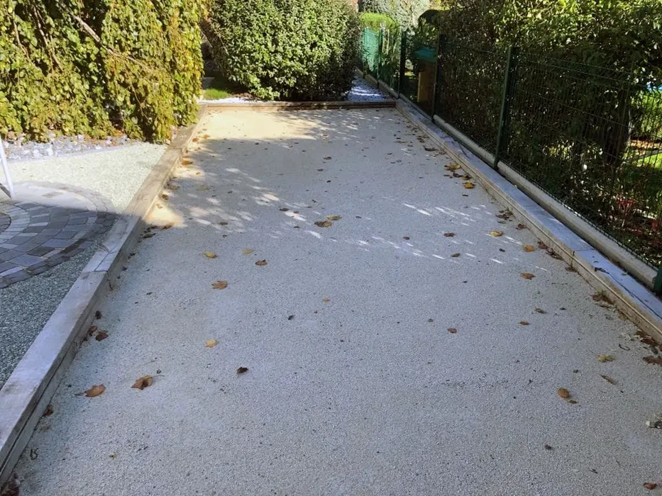 Terrasse extérieure en béton désactivé avec bordures en béton lissé, parsemée de feuilles mortes d'automne