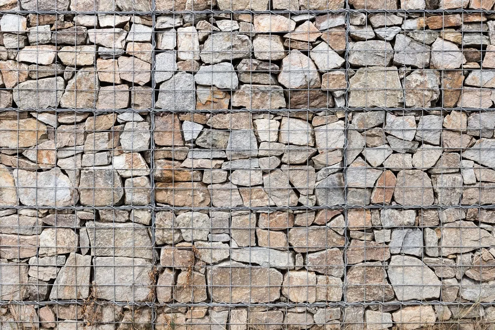 Mur de soutènement extérieur en gabions remplis de pierres naturelles de différentes tailles et teintes beiges à grises