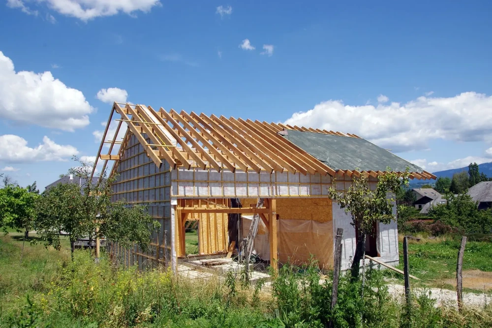 Chantier de construction résidentielle en cours, maison individuelle à ossature bois avec charpente traditionnelle apparente