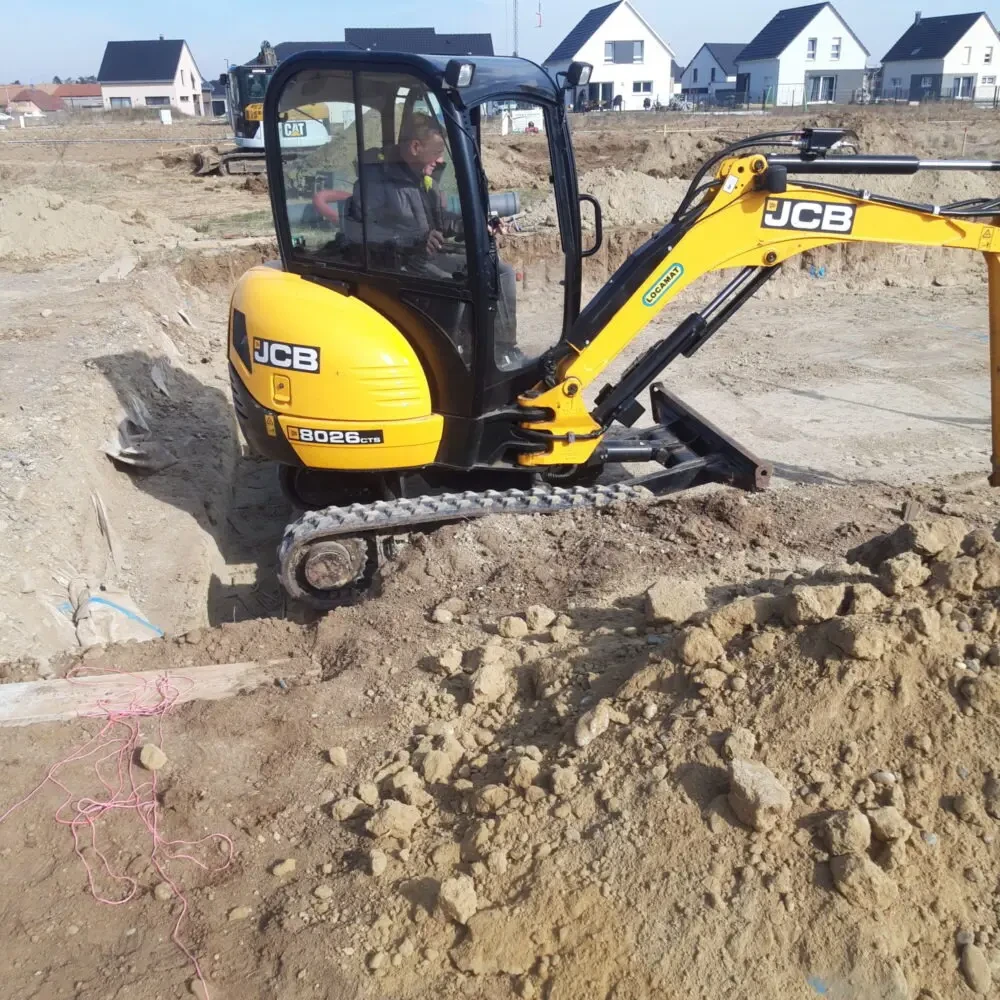 Chantier de terrassement extérieur avec pelleteuse hydraulique rouge en action sur terrain boueux