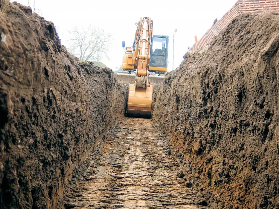 Chantier de construction en cours avec dalle béton fraîchement coulée délimitée par bandes de signalisation rouge et blanc