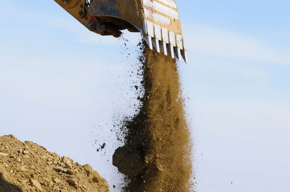 Chantier de terrassement au coucher du soleil avec pelleteuse hydraulique sur chenilles en activité